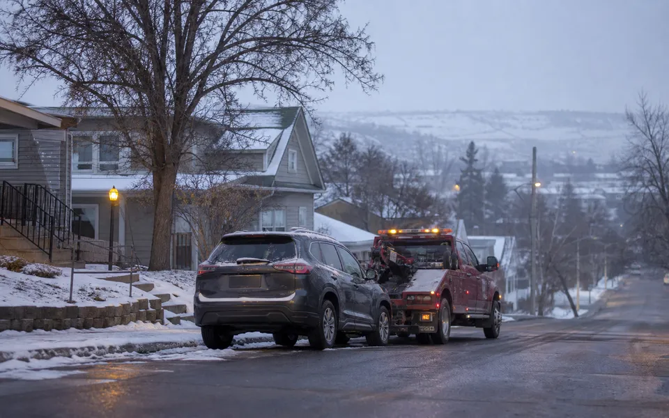 Tow truck assisting a dark SUV on a snowy residential hill in Pullman, Washington